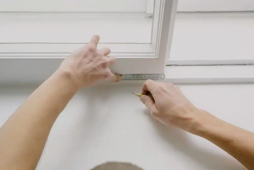 Tradesperson measuring aluminium window opening during a free measure and quote visit